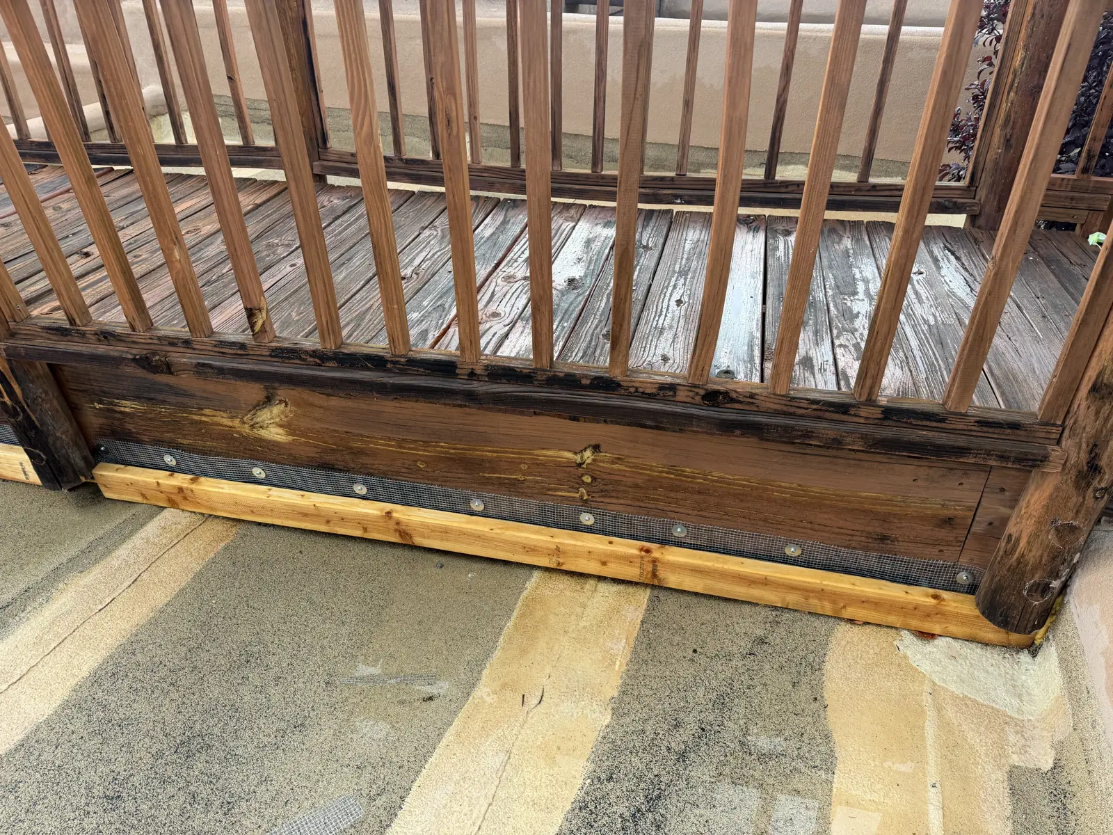 Galvanized mesh exclusion installed along the base of a wood deck
