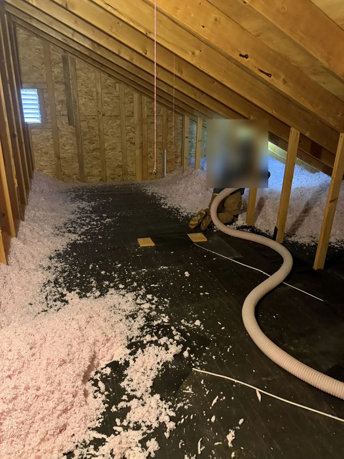 Fresh blown-in insulation being installed in a cleaned attic