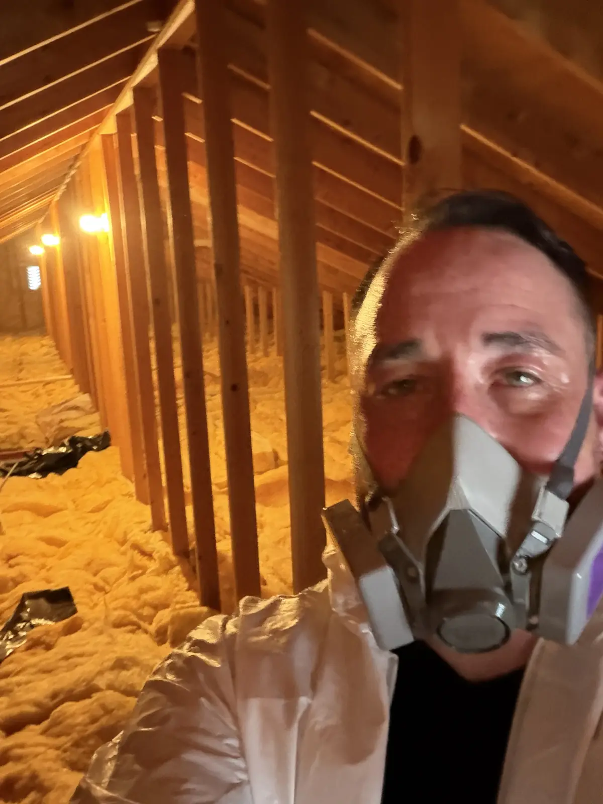 Owner Abel Valdez in a respirator and protective suit inside an attic during cleanup