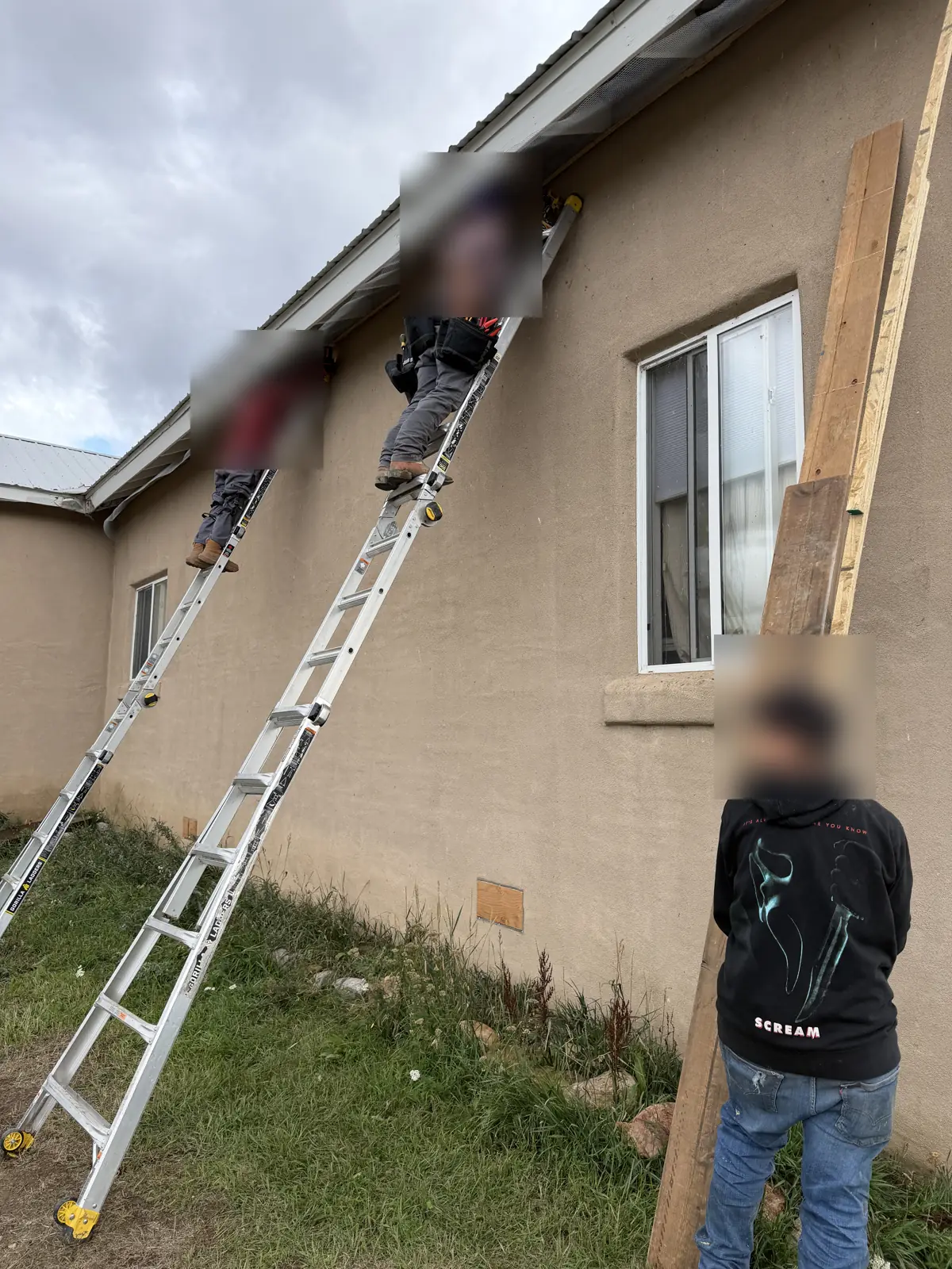 Technicians on ladders sealing roofline entry points on a stucco home