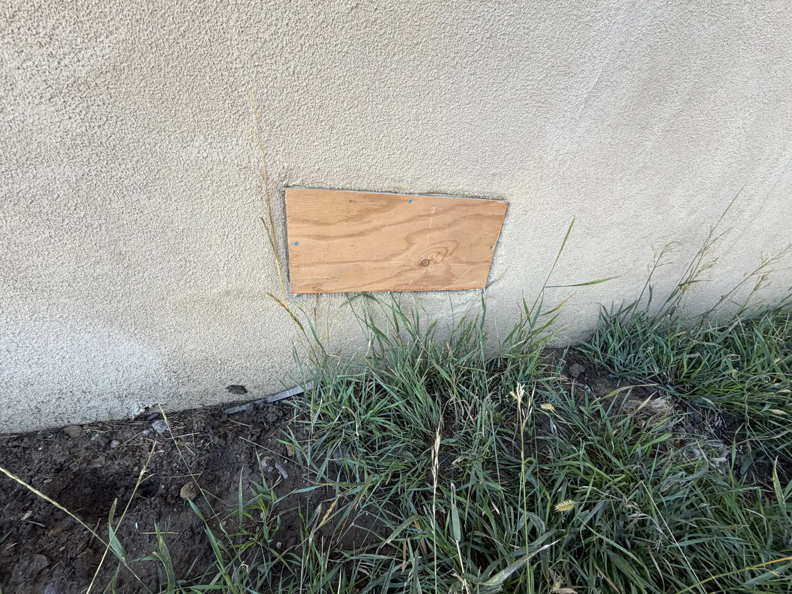 Exterior stucco wall with a repaired and sealed vent opening